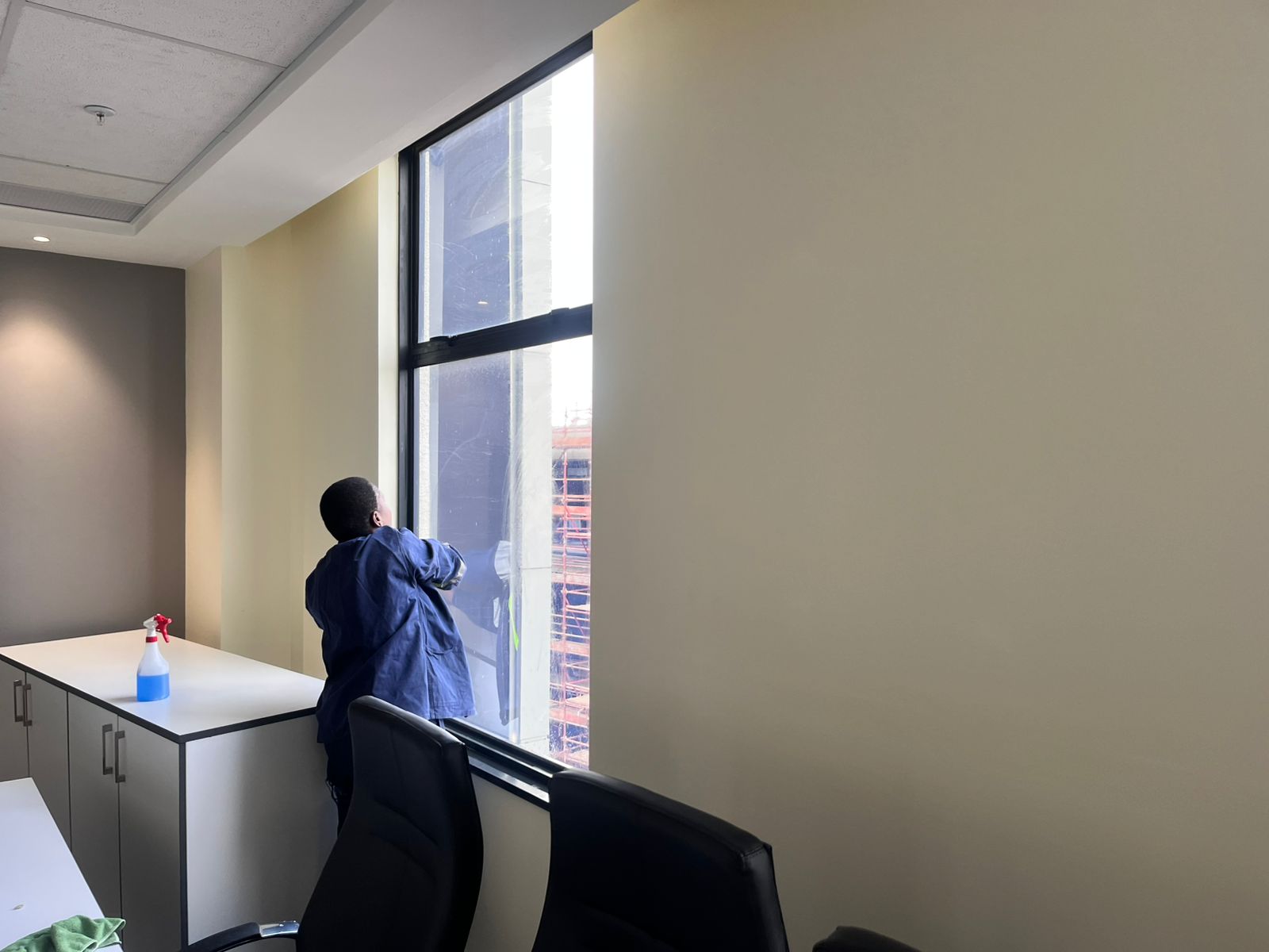 Office hallway with worker cleaning windows
